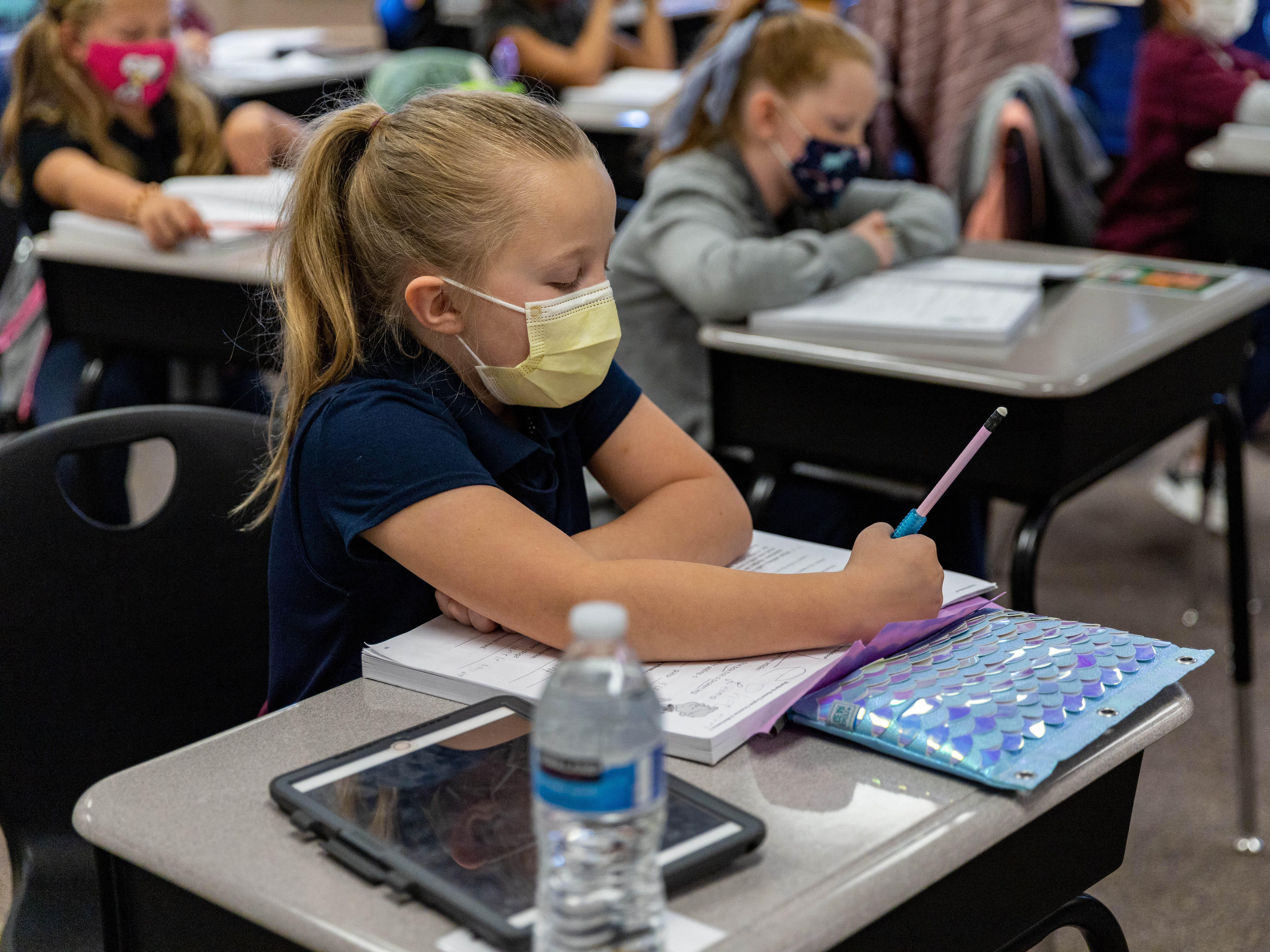 A young girl sits at a desk and writes in a notebook during a class in Park Elementary in the Steel Valley School District.