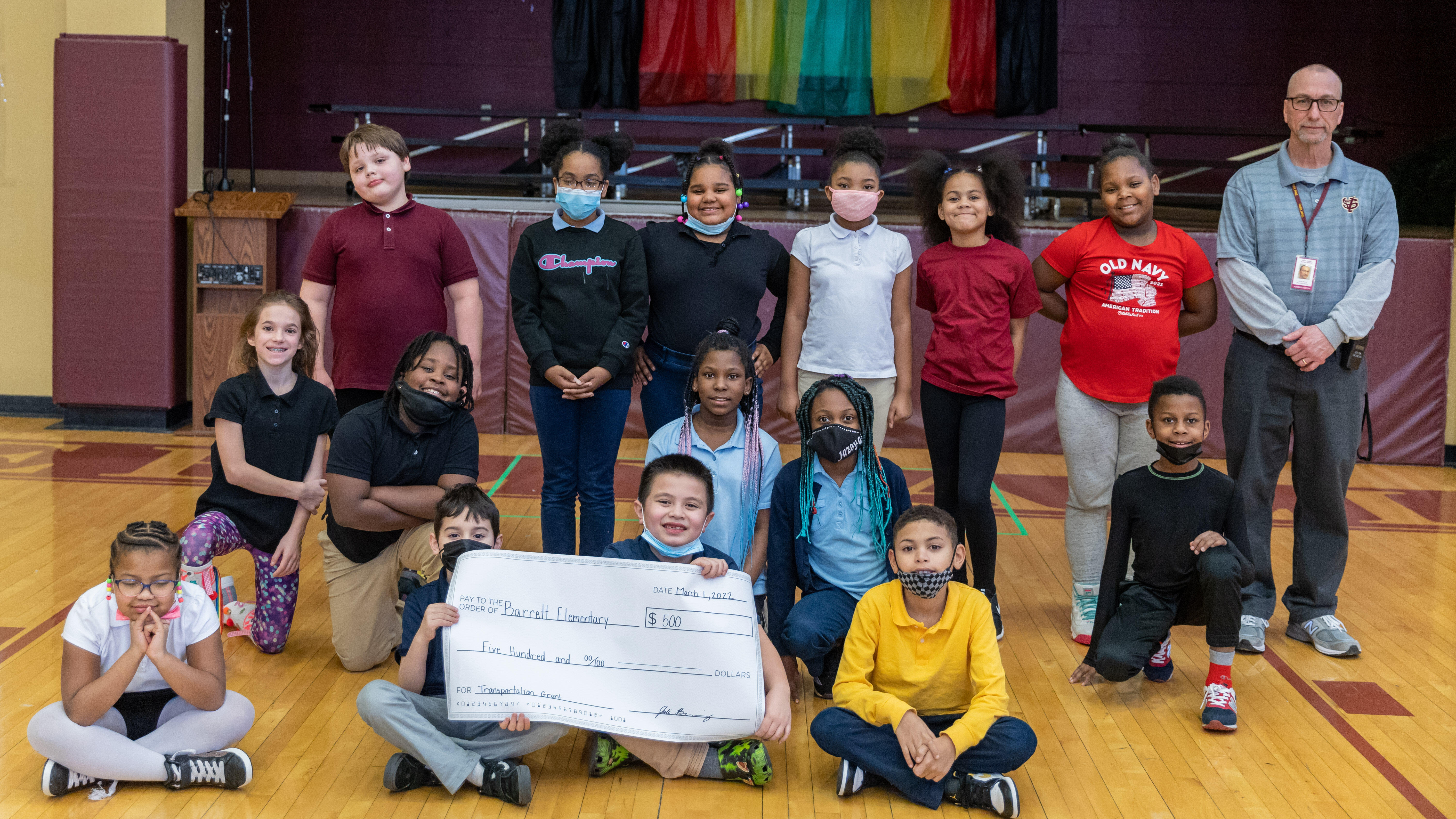 Students in Barrett's Kids of Steel program pose for a picture with a check for $500 that will help them compete in the Kids Marathon.
