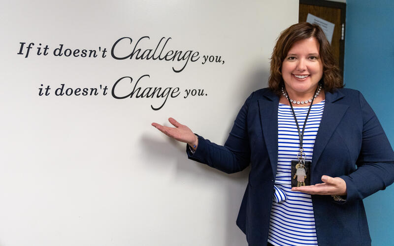 Steel Valley Director of Pupil Services Dr. Lisa Mumau stands next to a sign that reads "If it doesn't challenge you, it doesn't change you."