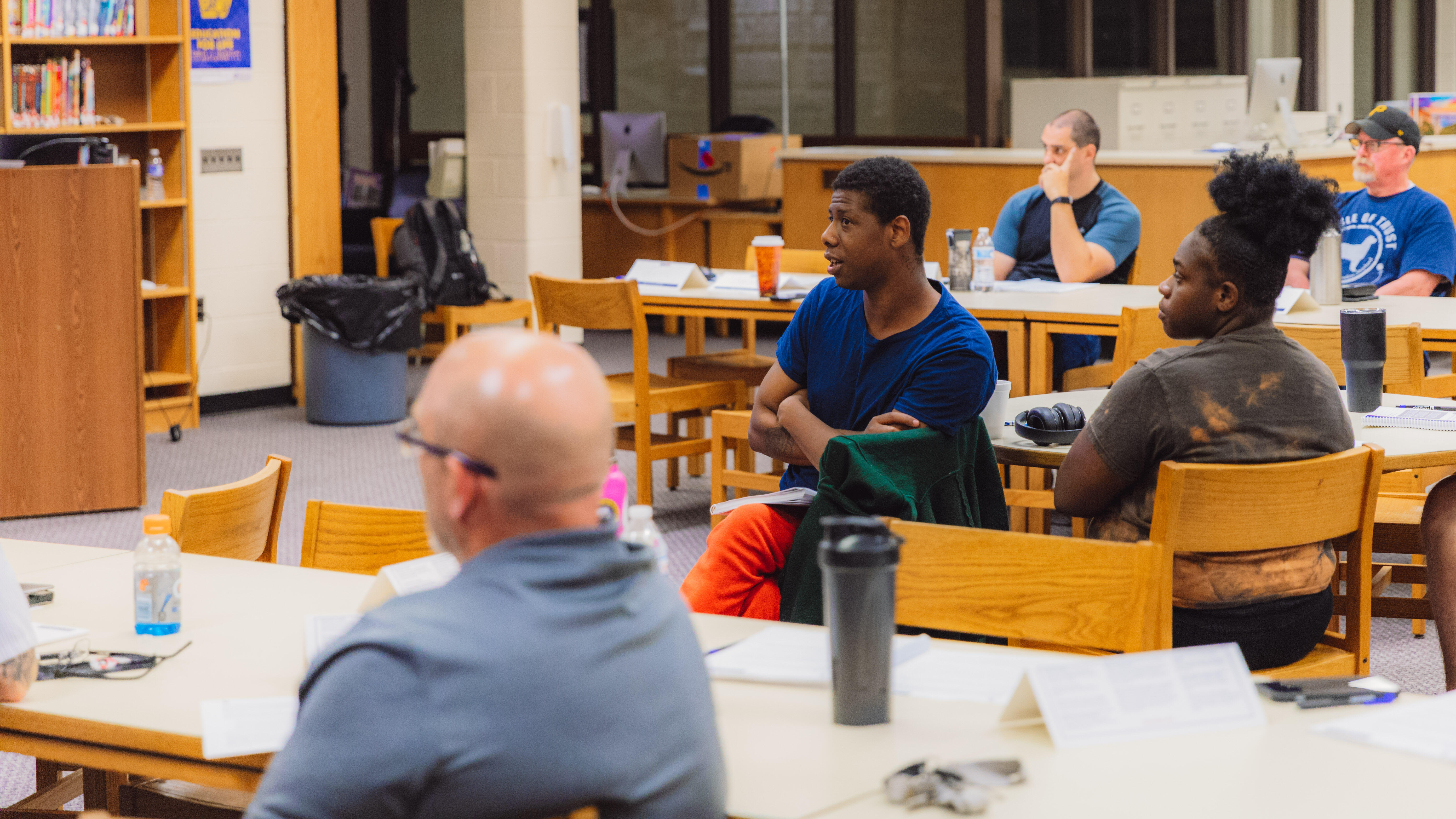 A student in a school resource officer training seminar asks a question while seated at a table