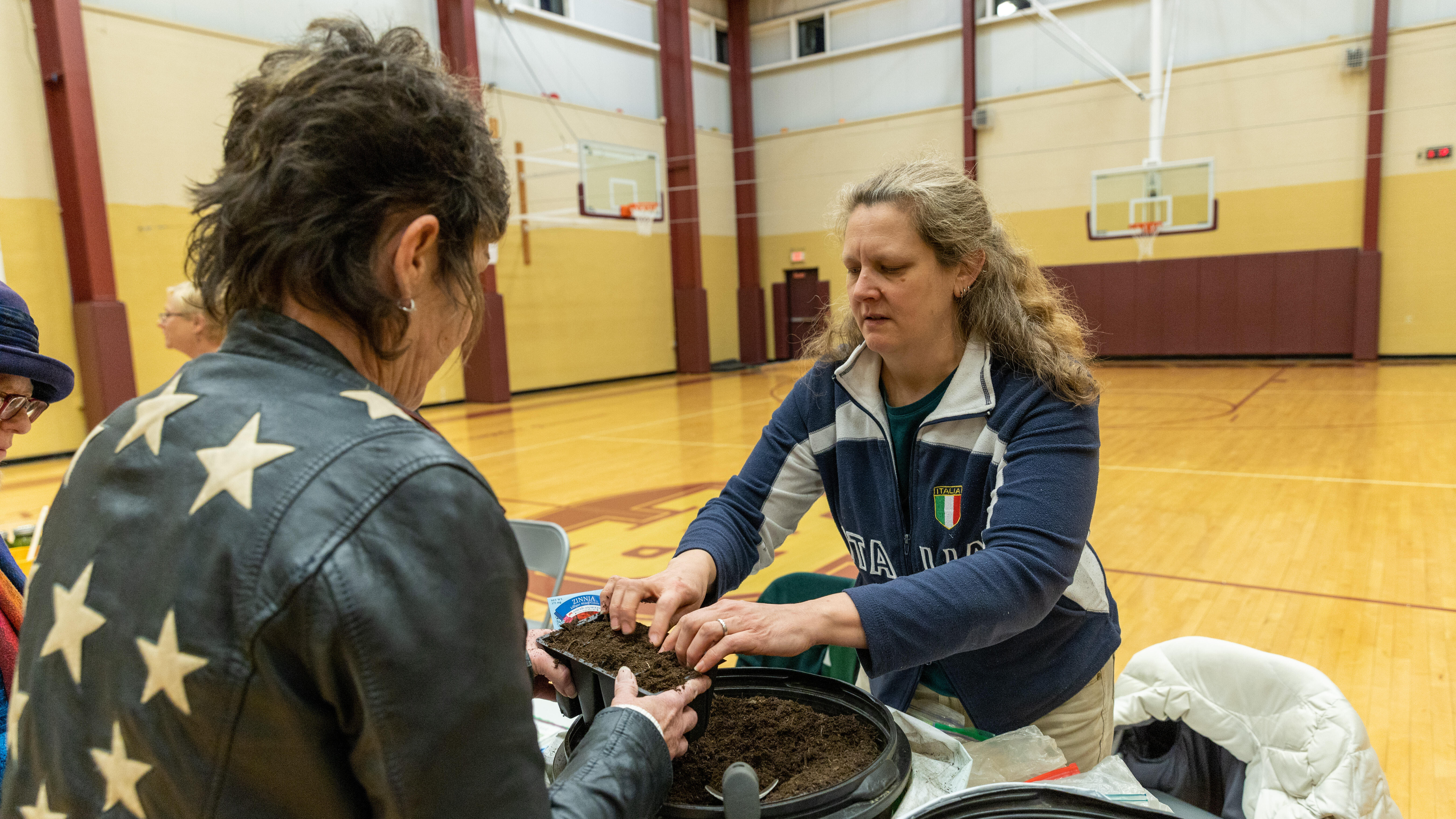 Christine Schott works with a community member to prep a plant pot