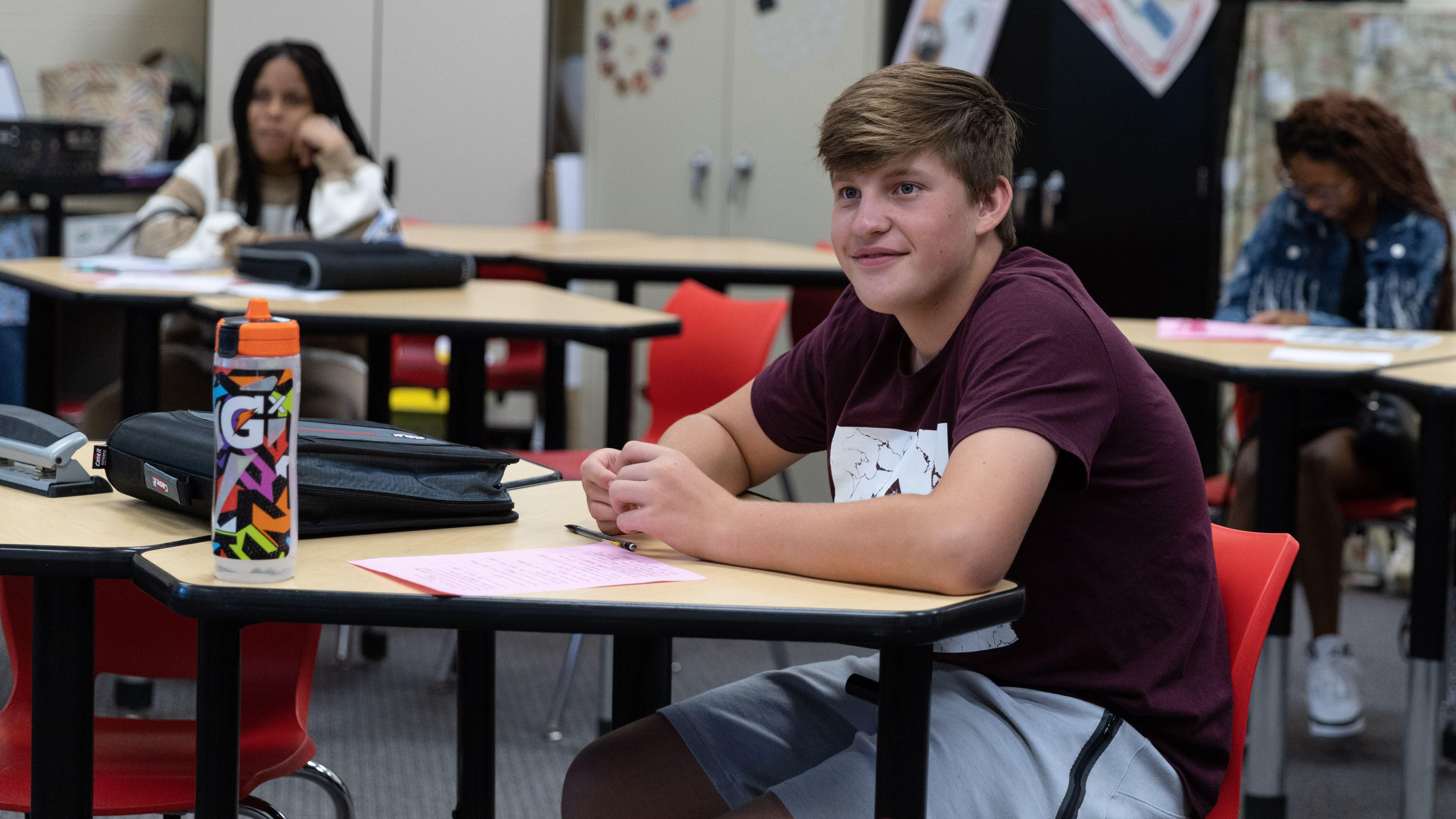 Middle school students laugh while seated in their desks
