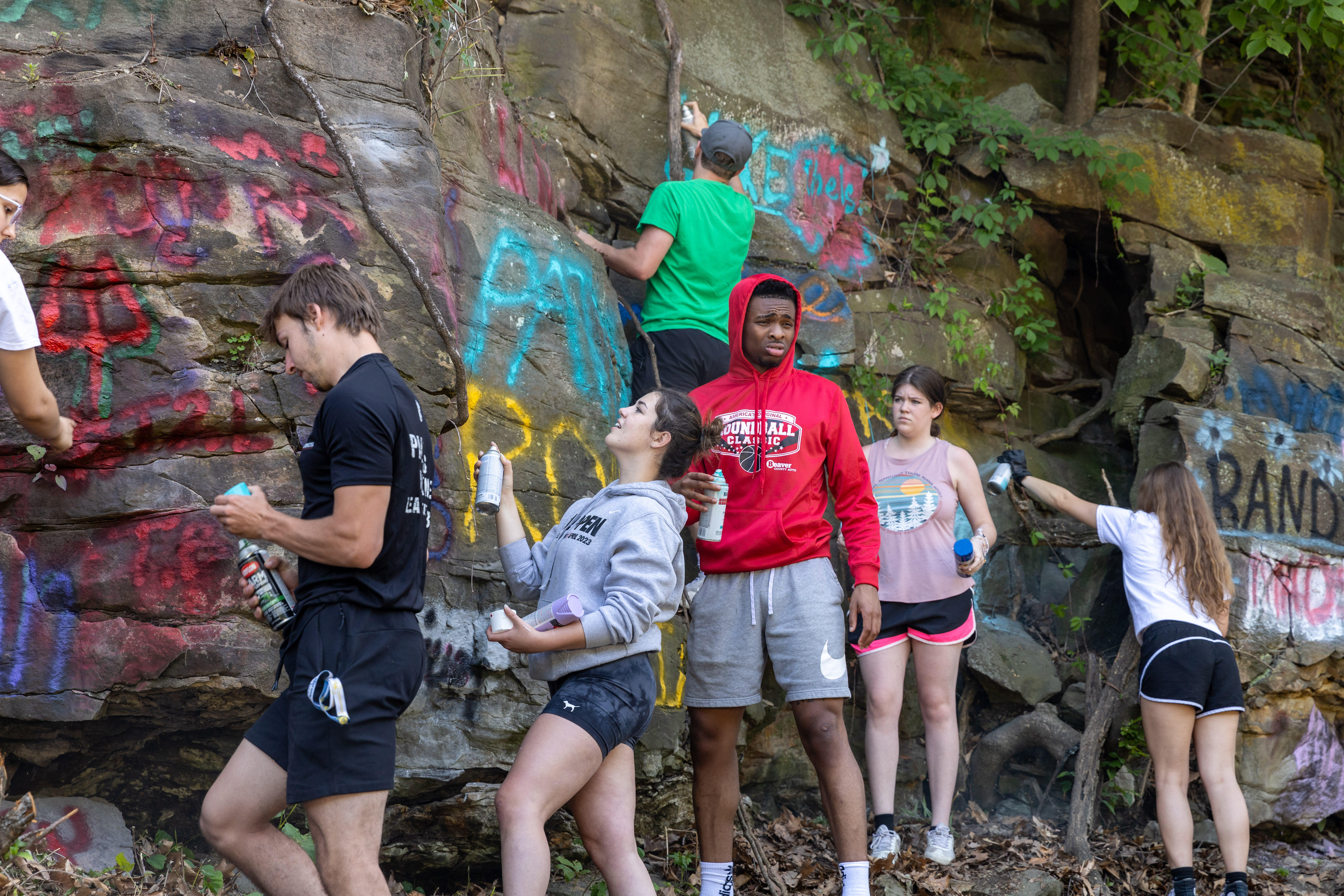 Students paint names on a rock wall