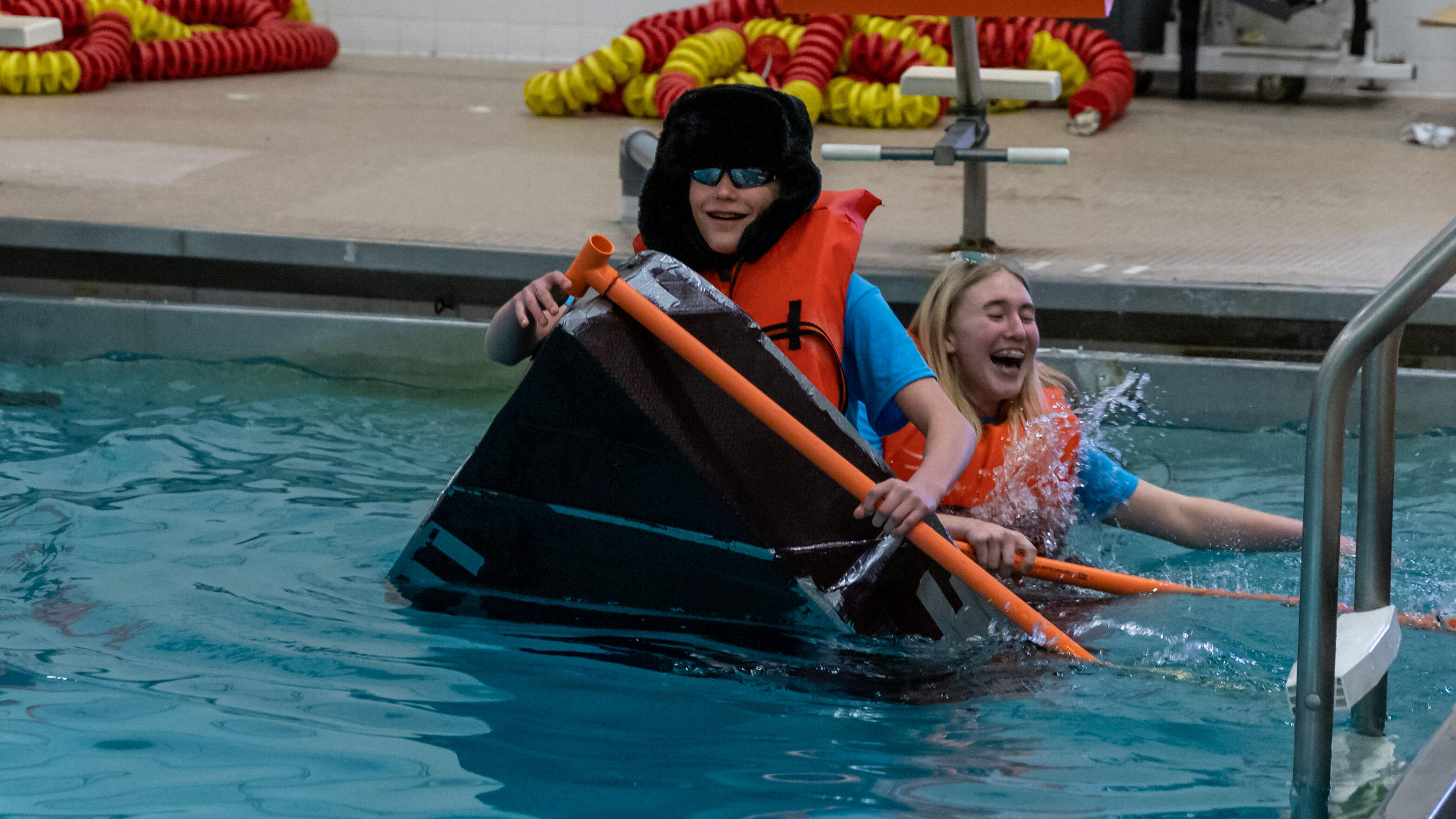 Middle school students attempt to cross the Steel Valley swimming pool in homemade boats.