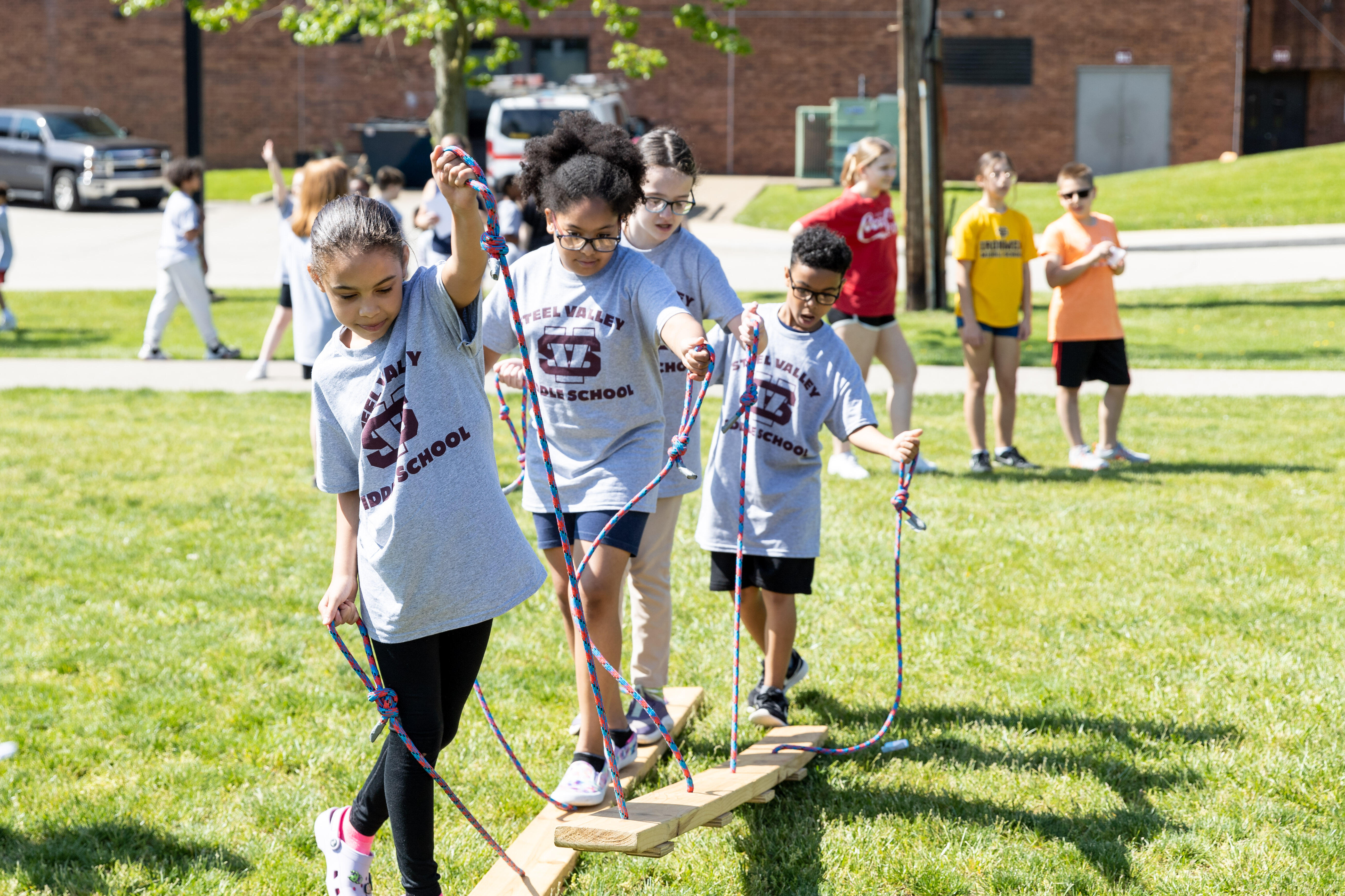 Students use ropes to pull up boards as part of a bonding activity