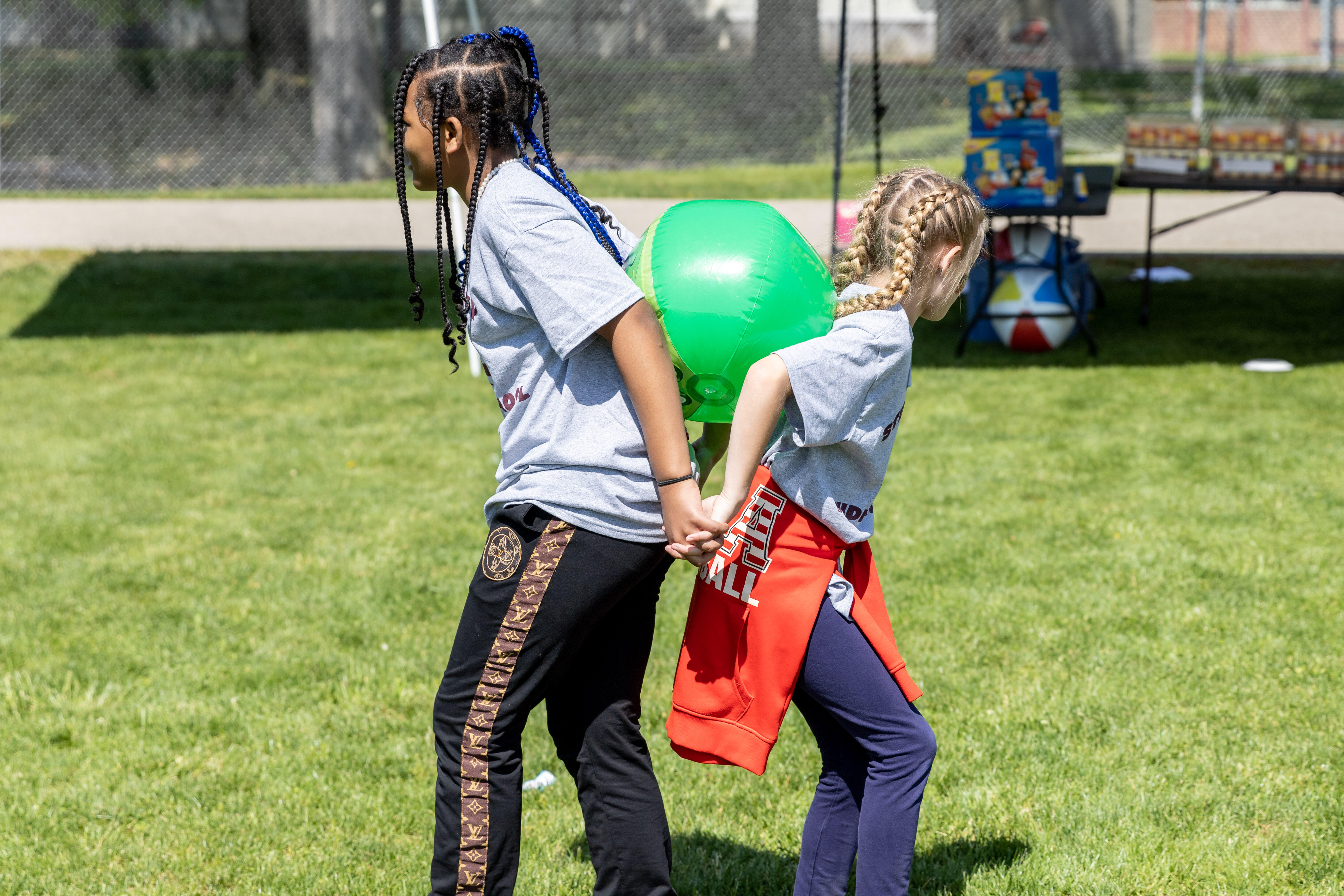 Two students work together to support an inflated ball pinned between their backs