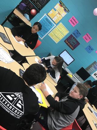 Students working on papers at a round table in the classroom