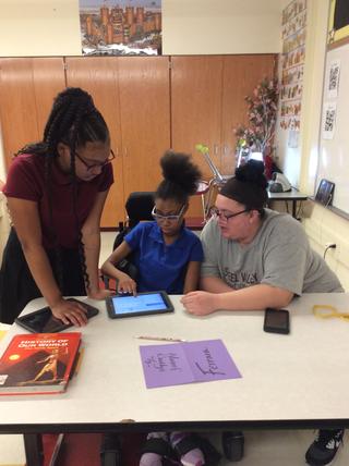 Three students work on tablet on desk